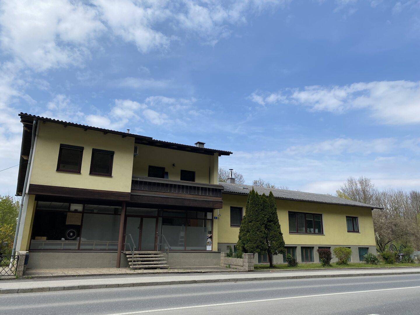Mehrstöckiges Gebäude mit gelber Fassade, Balkonen und großen Fenstern.