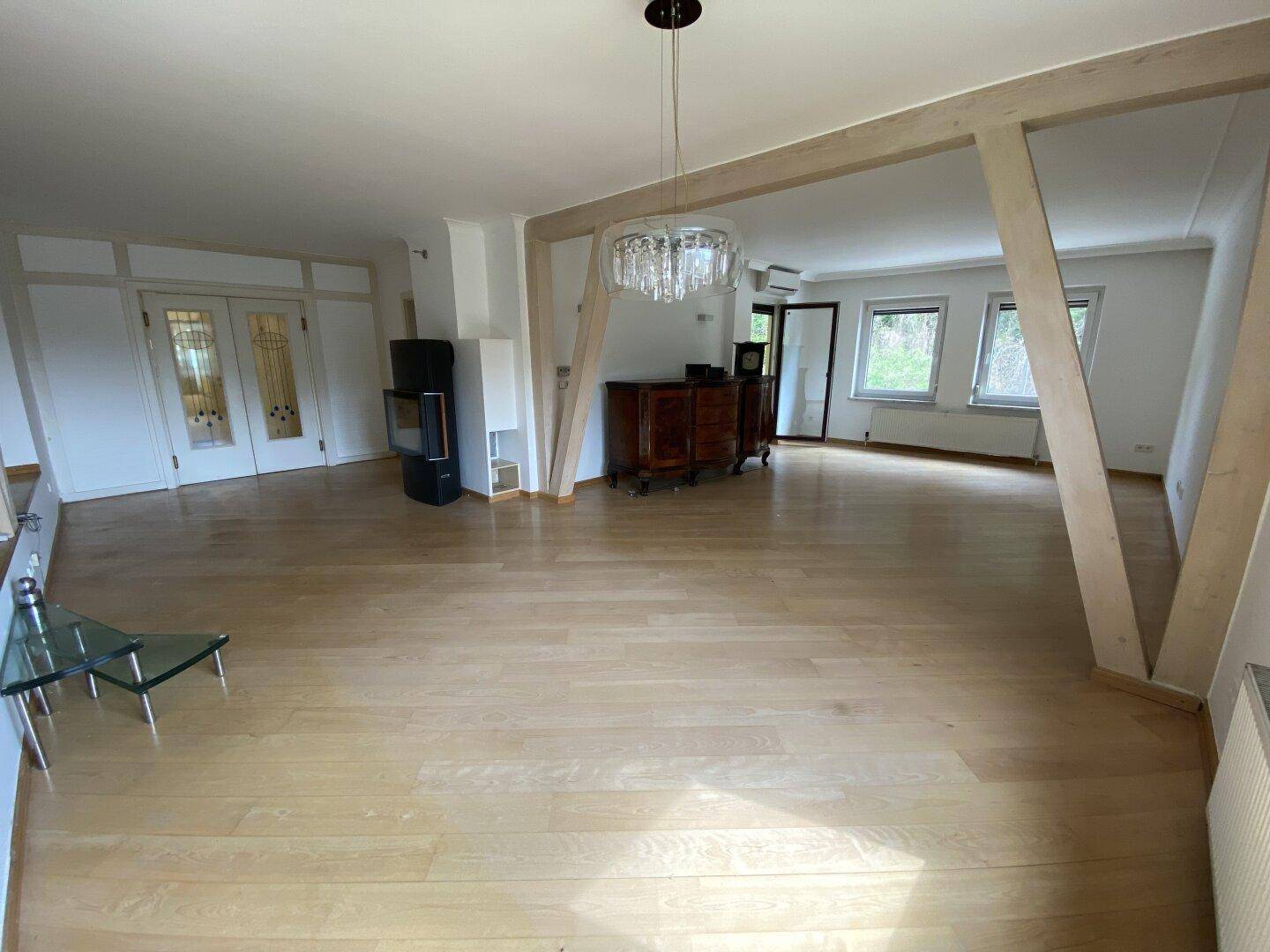 Heller Wohnbereich mit Parkettboden, Kaminofen und dekorativer Beleuchtung.