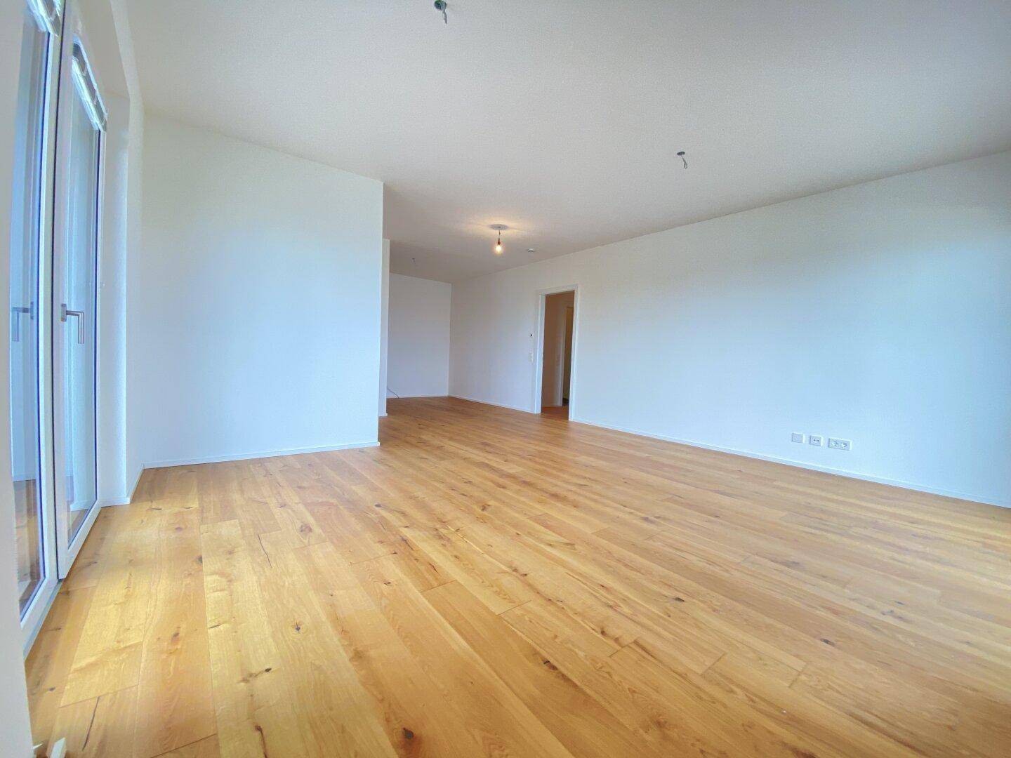 Heller Raum mit Holzboden und Zugang zu einem Außenbereich, ideal als Schlaf- oder Arbeitszimmer.