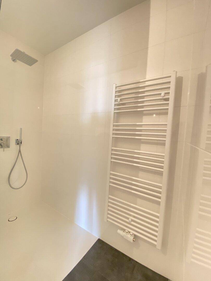 Ebenerdige Dusche mit Regenduschkopf und praktischem Handtuchheizkörper.