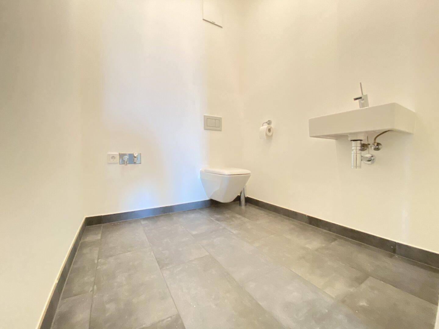 Modernes Gäste-WC mit wandhängender Toilette und kleinem Waschbecken.