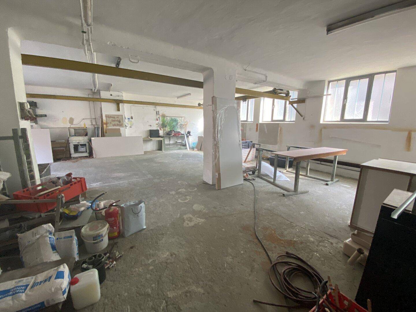 Ein weiterer Blick in den großen, hellen Werkstattraum mit Betonboden und mehreren Fenstern, bereit zur Umgestaltung.