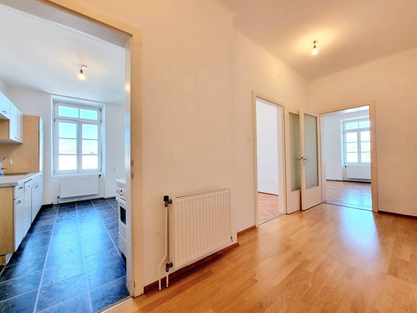 Heller Flur mit Parkettboden, der zu verschiedenen Zimmern und einer Küche führt.