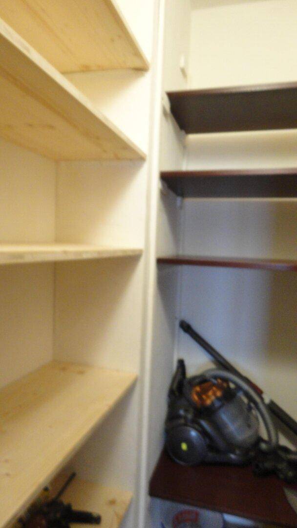 Praktischer Abstellraum mit mehreren Holzregalen für zusätzlichen Stauraum und Haushaltsgeräte.