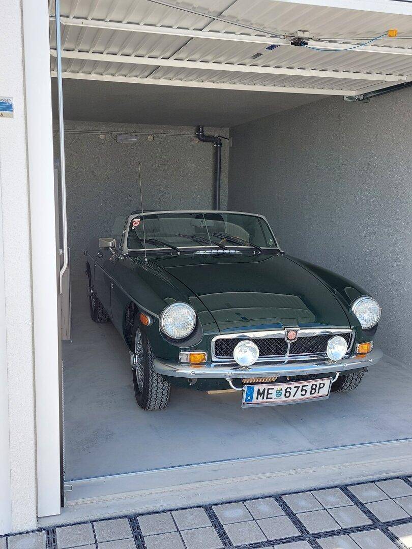 Ein klassischer grüner Sportwagen parkt in einer sauberen, modernen Einzelgarage mit Betonboden.