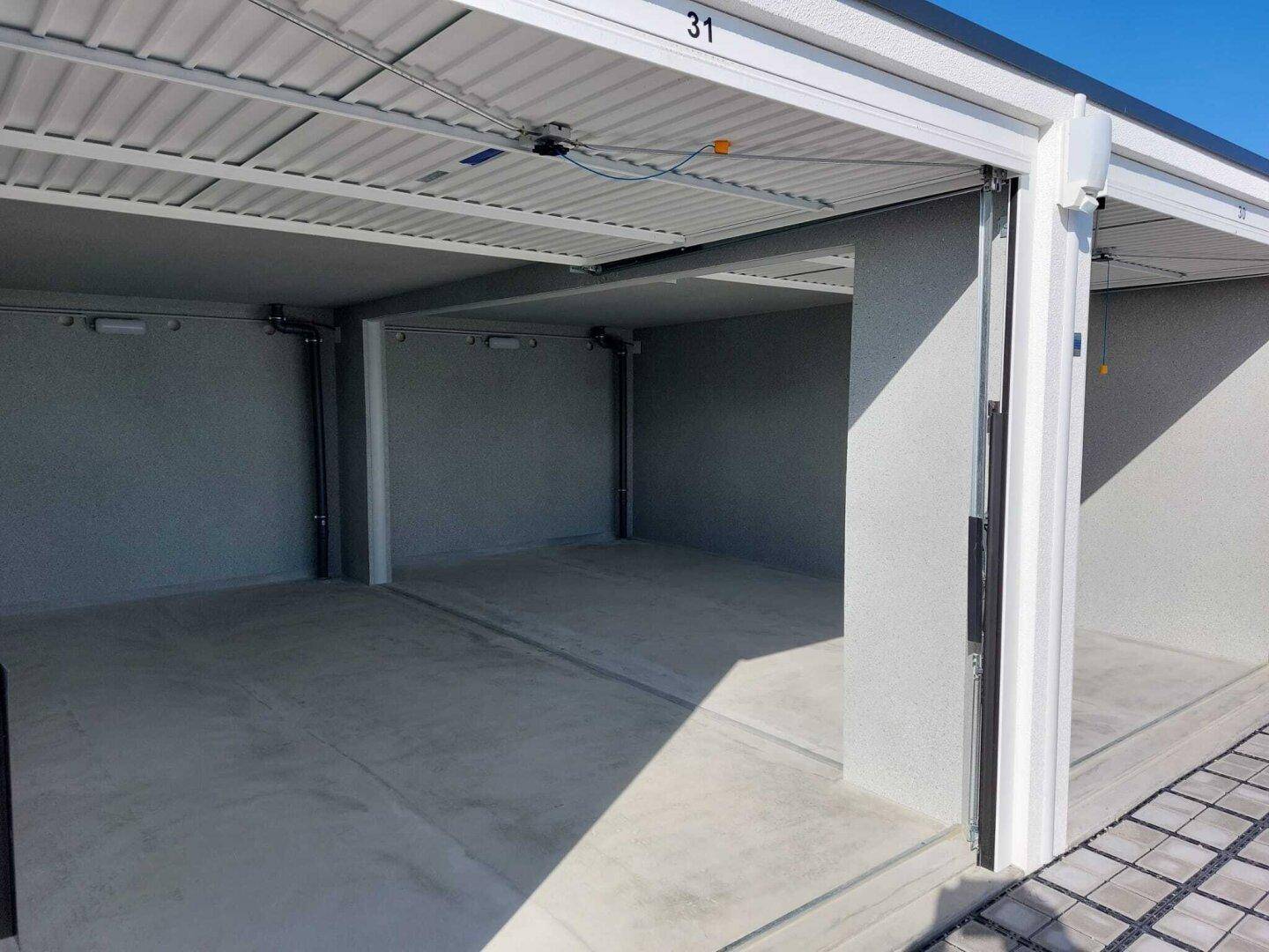Leere, saubere Garage mit Betonboden und grauen Wänden, bereit zur Nutzung.