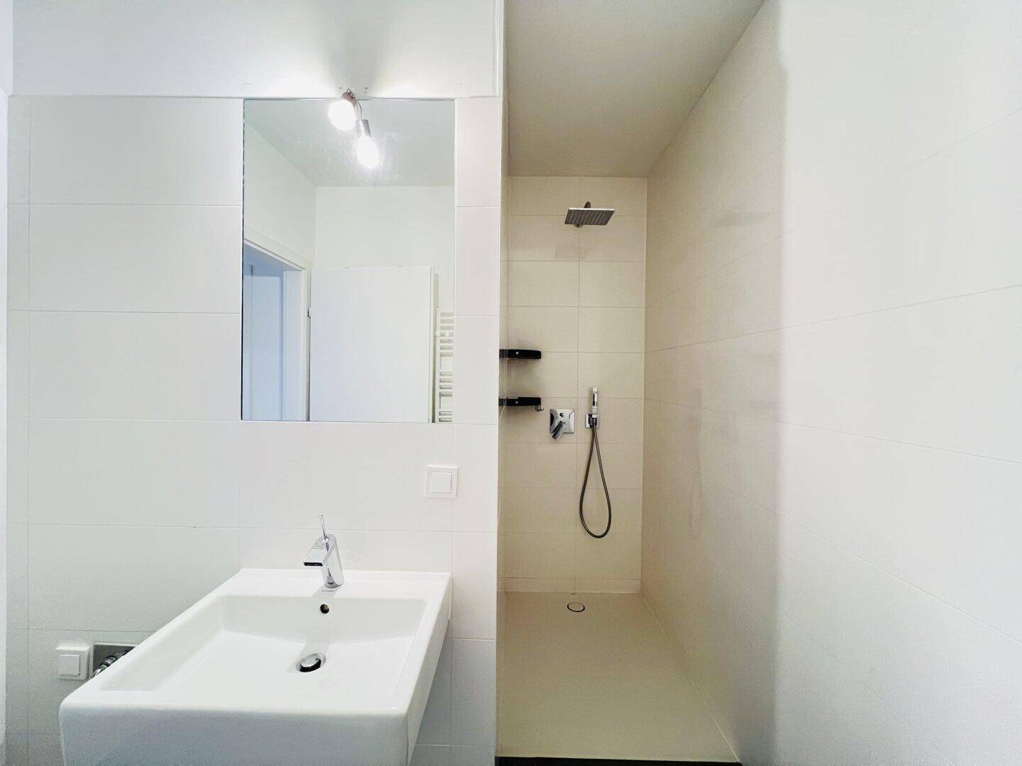 Modernes Badezimmer mit ebenerdiger Dusche, weiß gefliest und minimalistischem Design.