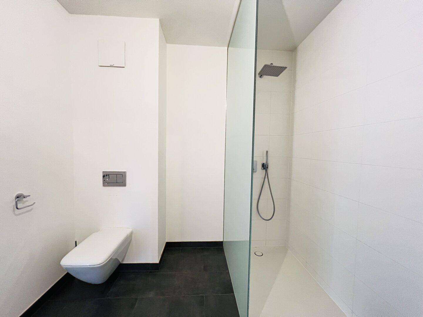 Elegantes Badezimmer mit wandhängendem WC und einer geräumigen begehbaren Dusche mit Regenduschkopf.