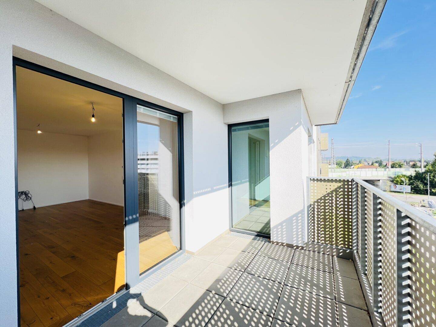Heller Balkon mit Fliesenboden und moderner Lochblech-Brüstung.