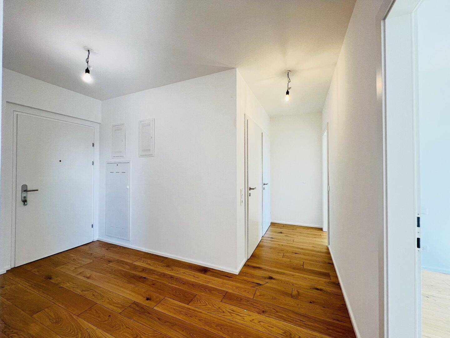 Heller Eingangsbereich mit Holzboden und weißen Wänden.