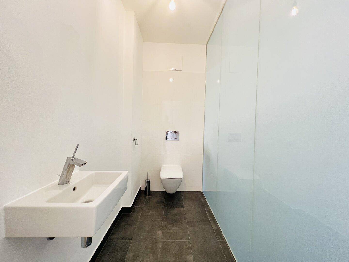Modernes Gäste-WC mit wandhängender Toilette und kleinem Waschbecken.