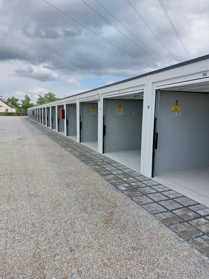 Eine Reihe von Garagenboxen mit geöffneten Toren, die einen Blick auf die leeren Innenräume freigeben.