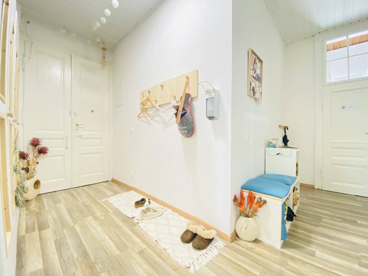 Freundlicher Eingangsbereich mit Garderobe, Schuhbank und hellem Laminatboden, einladend gestaltet.
