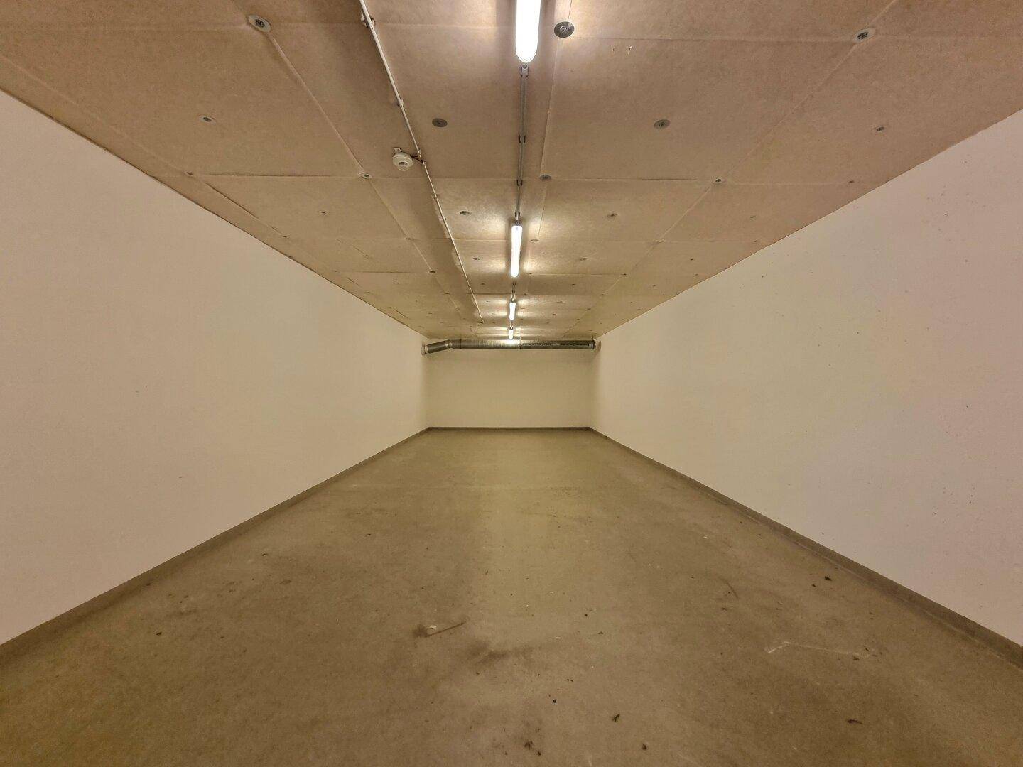 Geräumiger Lagerraum mit Betonboden und einfacher Beleuchtung, bietet viel Platz für verschiedene Nutzungen.