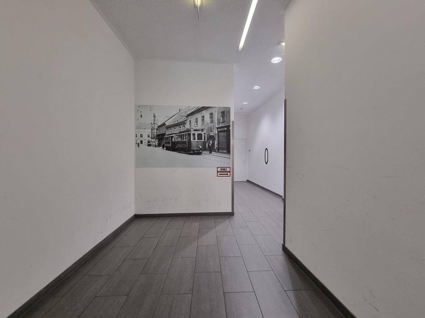 Heller Flur mit modernen Fliesen und einer historischen Schwarz-Weiß-Fotografie an der Wand als Dekoration.