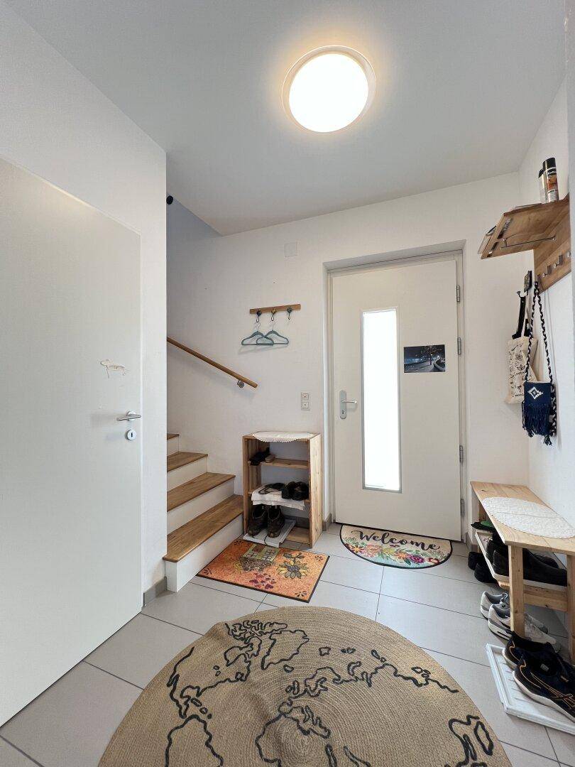 Heller Eingangsbereich mit Fliesenboden, Garderobe und Treppe zum Obergeschoss.