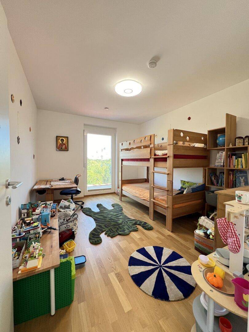 Kinderzimmer mit Etagenbett, Schreibtisch und Holzboden, ideal zum Spielen und Lernen.