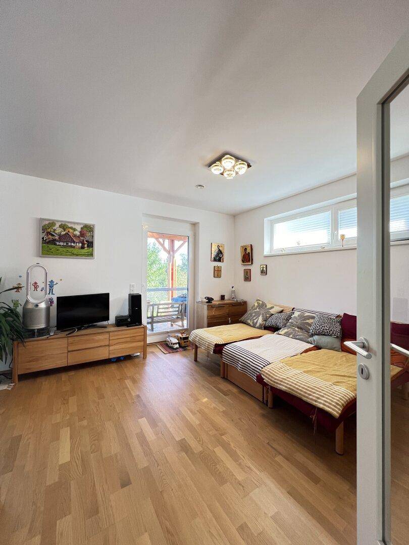 Gemütliches Wohnzimmer mit Holzboden, Sofa und Zugang zu einem Außenbereich.