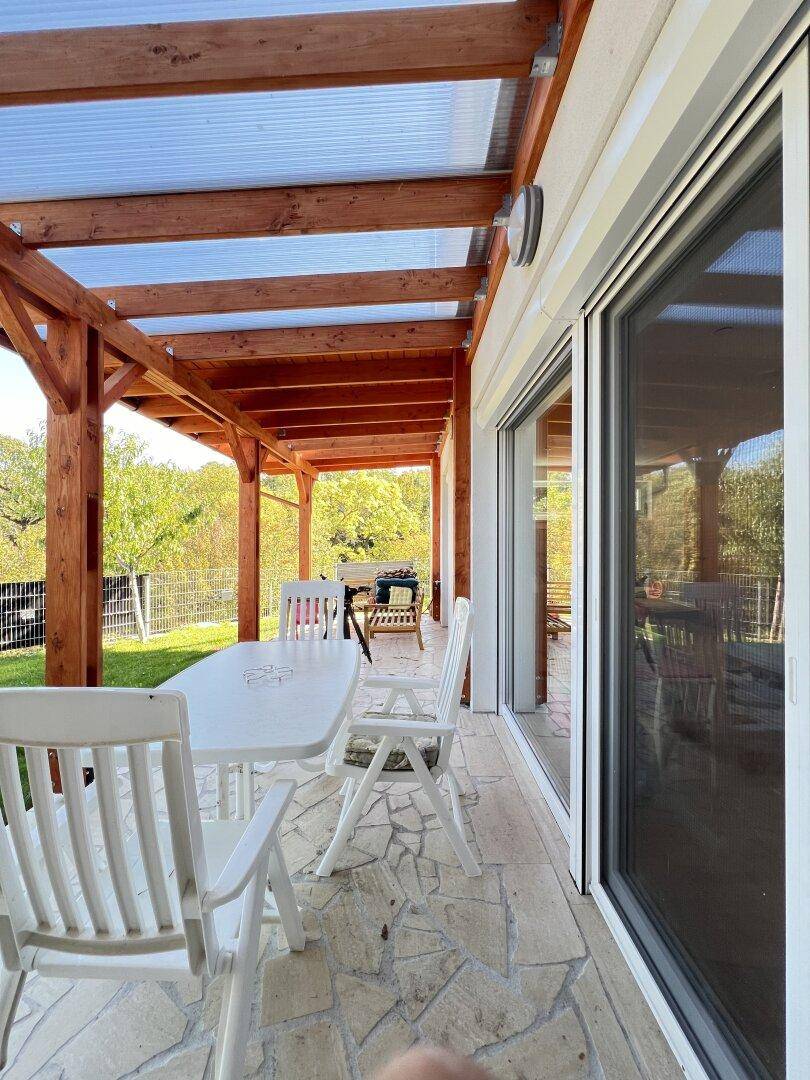 Überdachte Terrasse mit Holzbalken und Gartenmöbeln, ideal für entspannte Stunden im Freien.