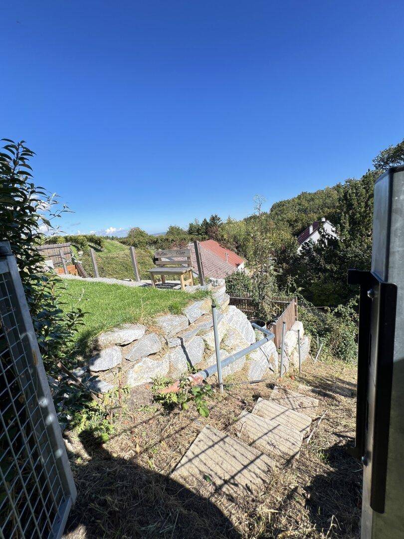 Gartenweg auf einem Hanggrundstück mit Steinen und Blick auf die umliegende Landschaft.