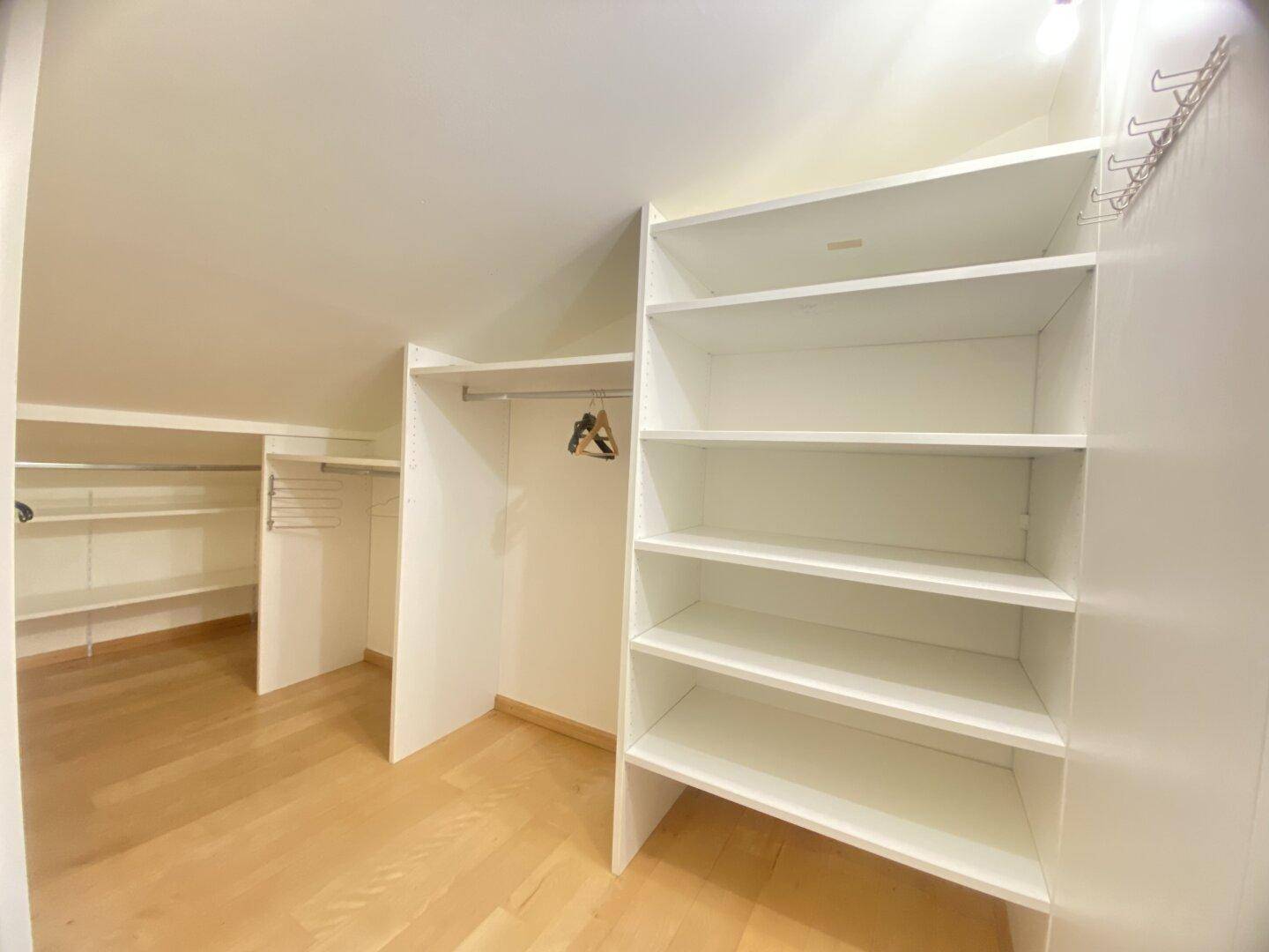 Begehbarer Kleiderschrank mit Regalen und Stauraum im Dachgeschoss.