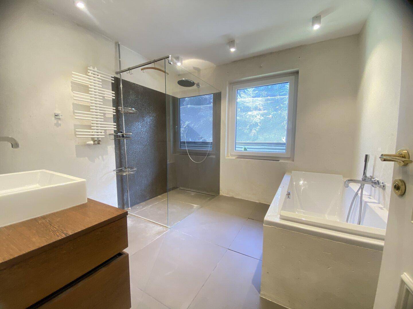 Modernes Badezimmer mit Badewanne, begehbarer Dusche und beheiztem Handtuchhalter.