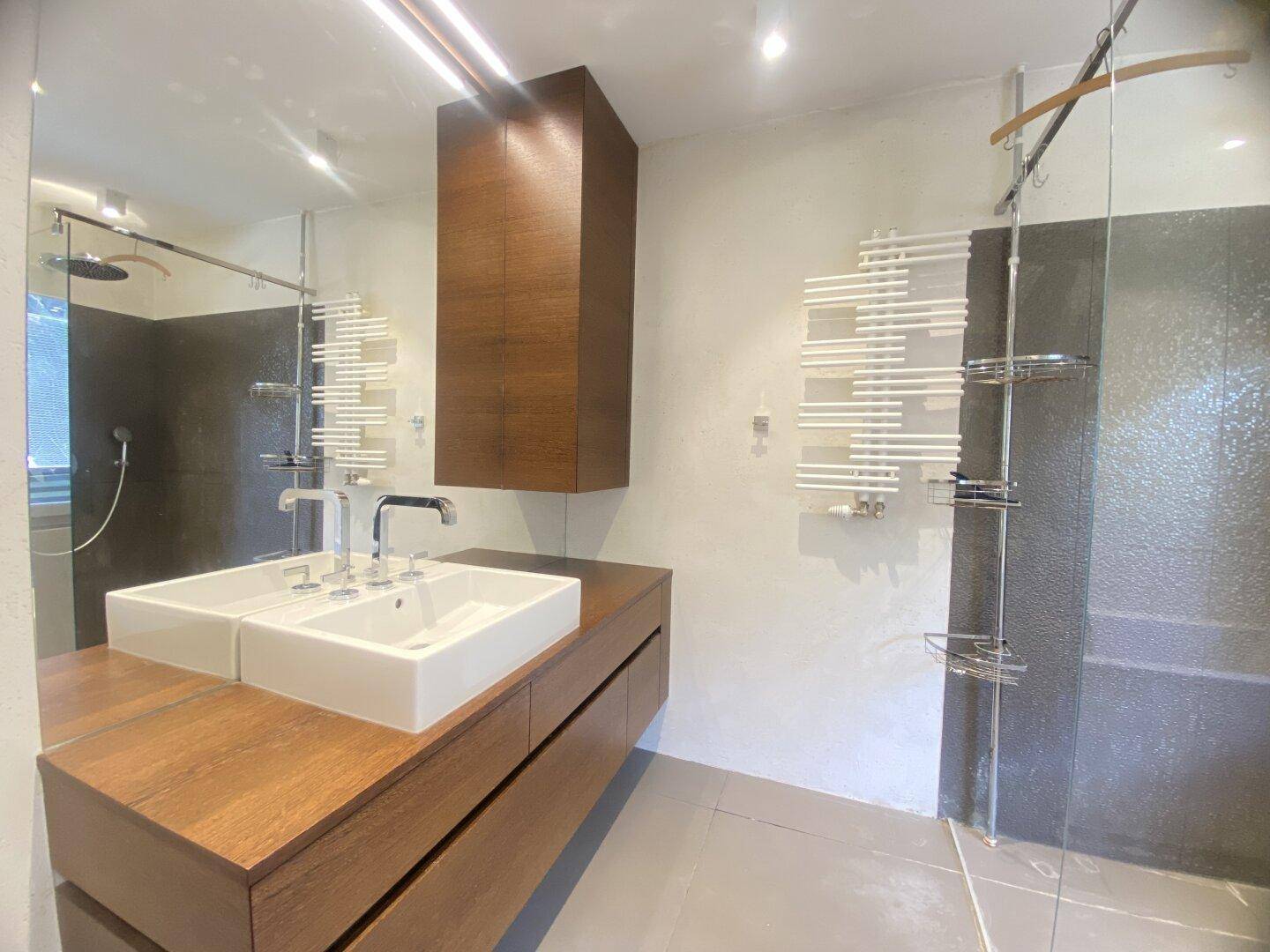Modernes Badezimmer mit Doppelwaschbecken, großem Spiegel und begehbarer Dusche.