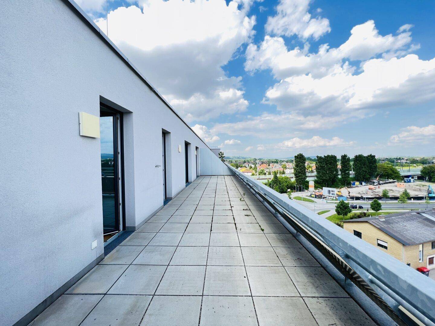 Weitläufige Dachterrasse mit Fliesenboden und Panoramablick über die Stadt und Umgebung.