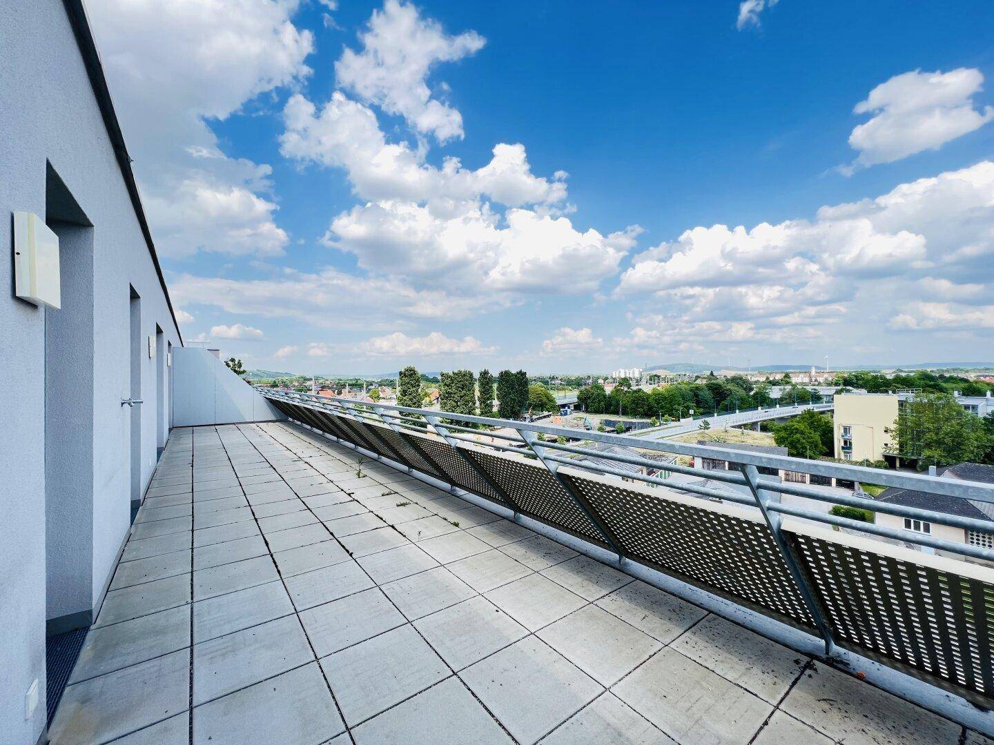 Große, geflieste Terrasse mit moderner Brüstung und weitem Blick über die Landschaft.