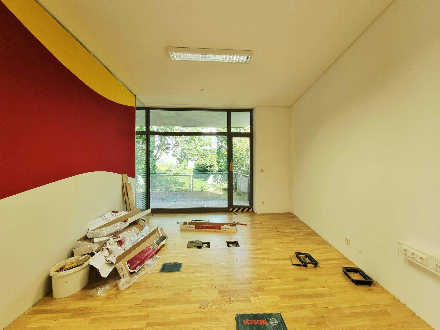 Heller Raum mit Holzboden und farbiger Wand, bereit für die Installation neuer Bodenbeläge.