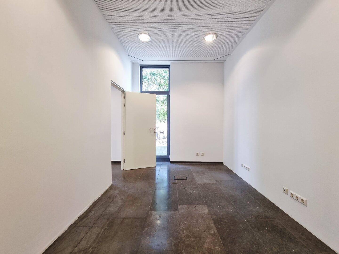 Kleinerer Raum mit Fliesenboden und Fenster, ideal für ein Einzelbüro oder Lager.