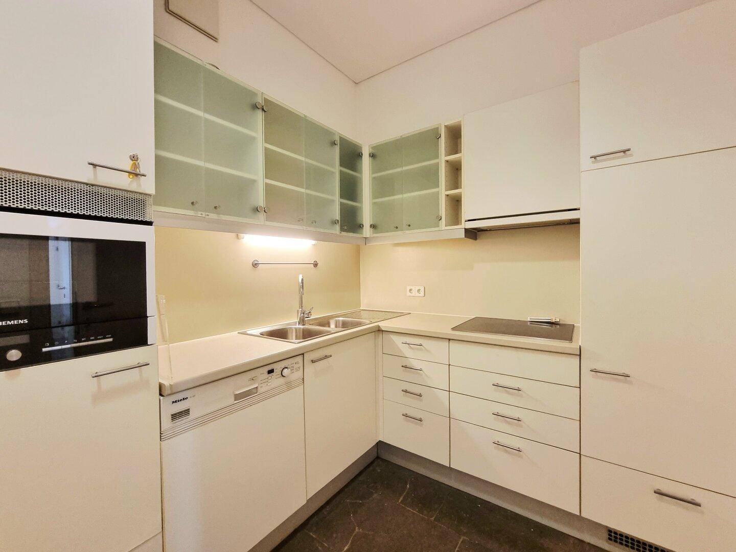 Moderne Einbauküche mit weißen Schränken, integrierten Geräten und viel Stauraum.