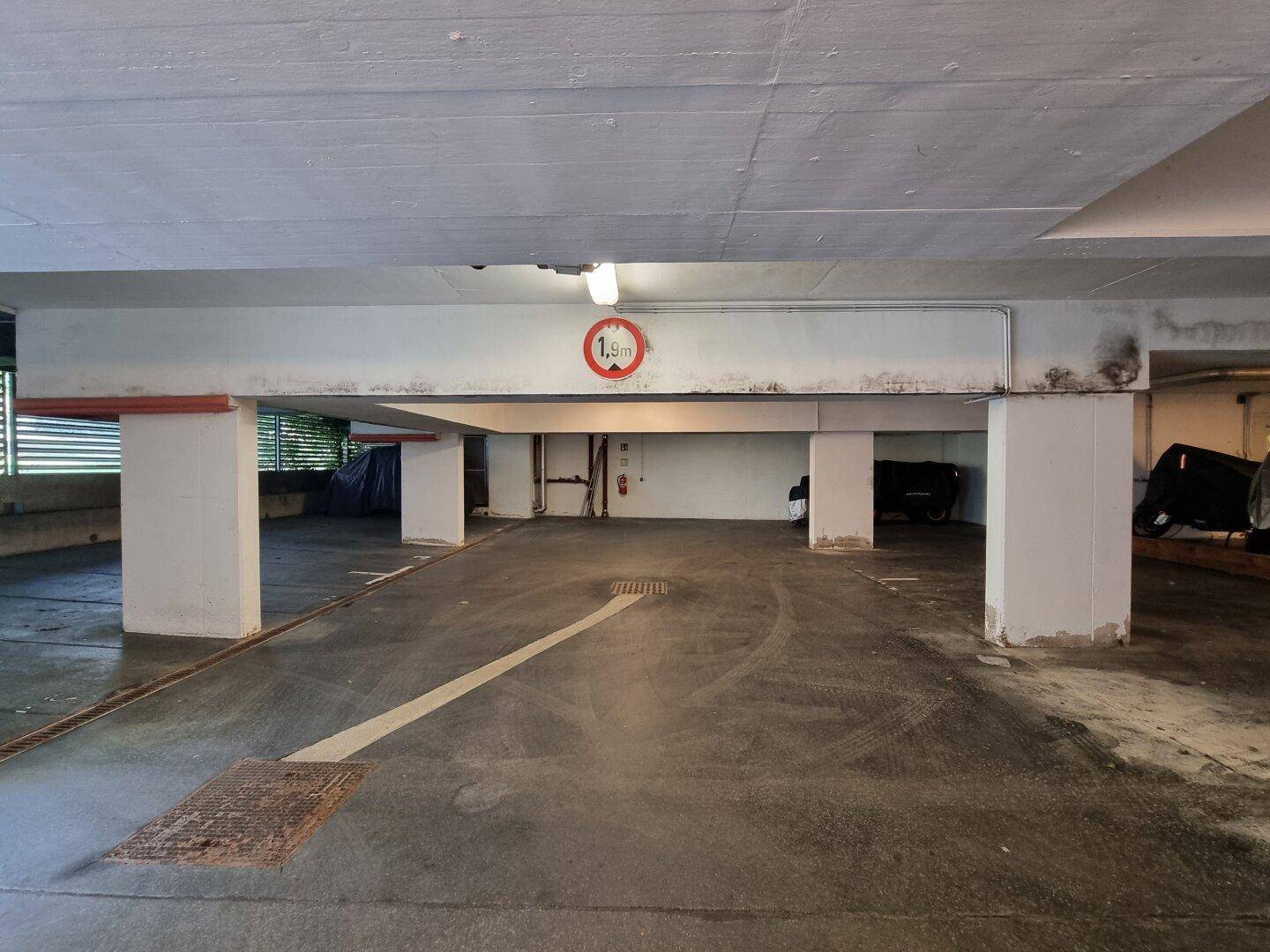 Tiefgarage mit Betonstützen und Höhenbegrenzung, bietet sichere Stellplätze.