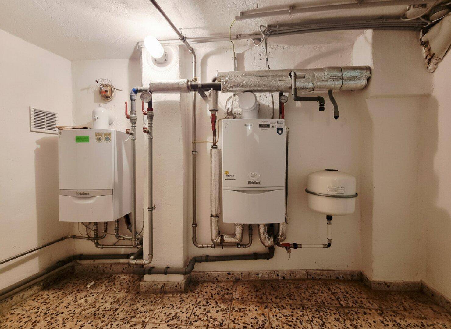 Heizungsraum mit zwei modernen Heizkesseln und Rohrleitungen.