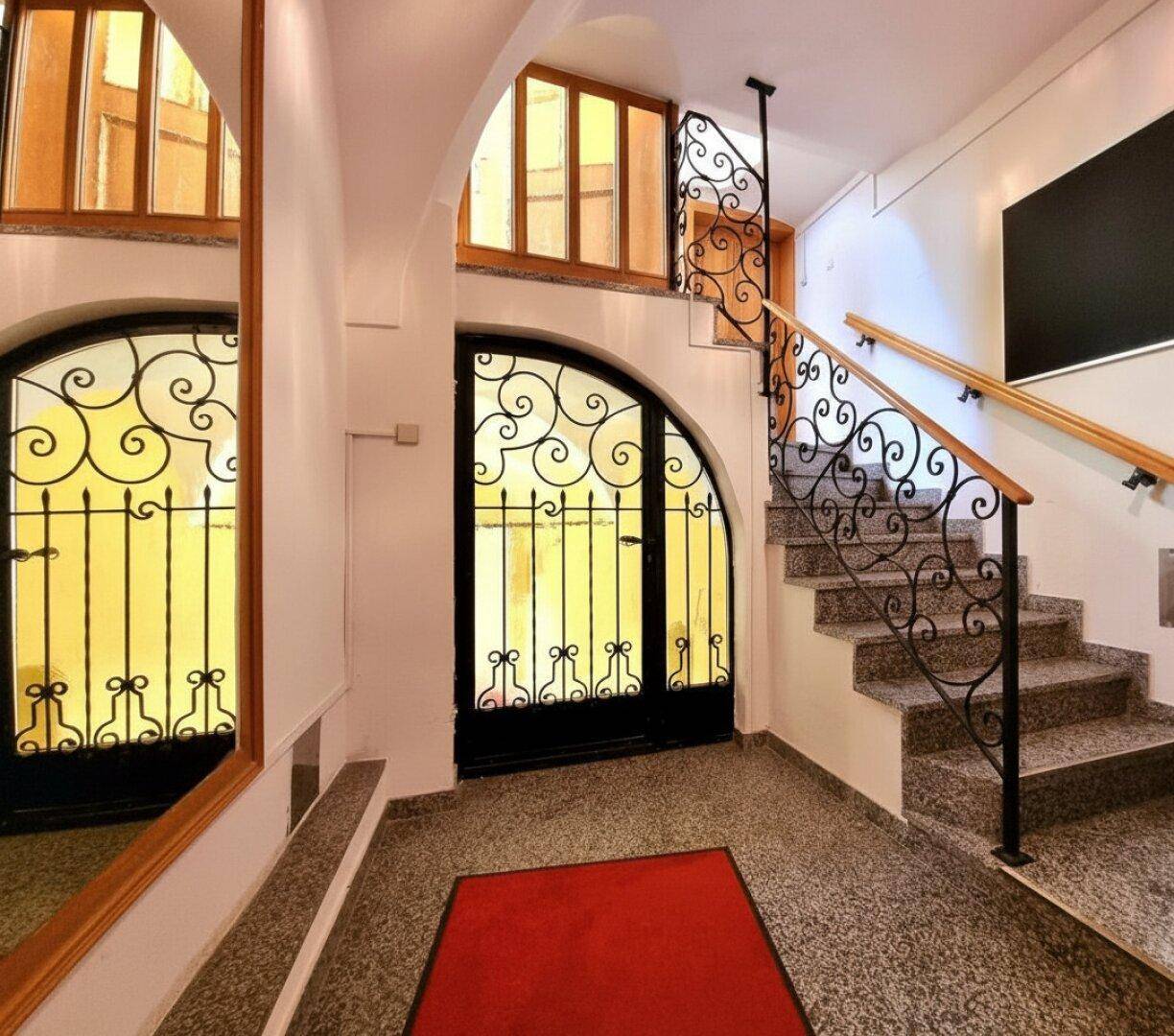 Eingangsbereich mit Granitboden, schmiedeeisernem Geländer und Treppe zu den oberen Etagen.