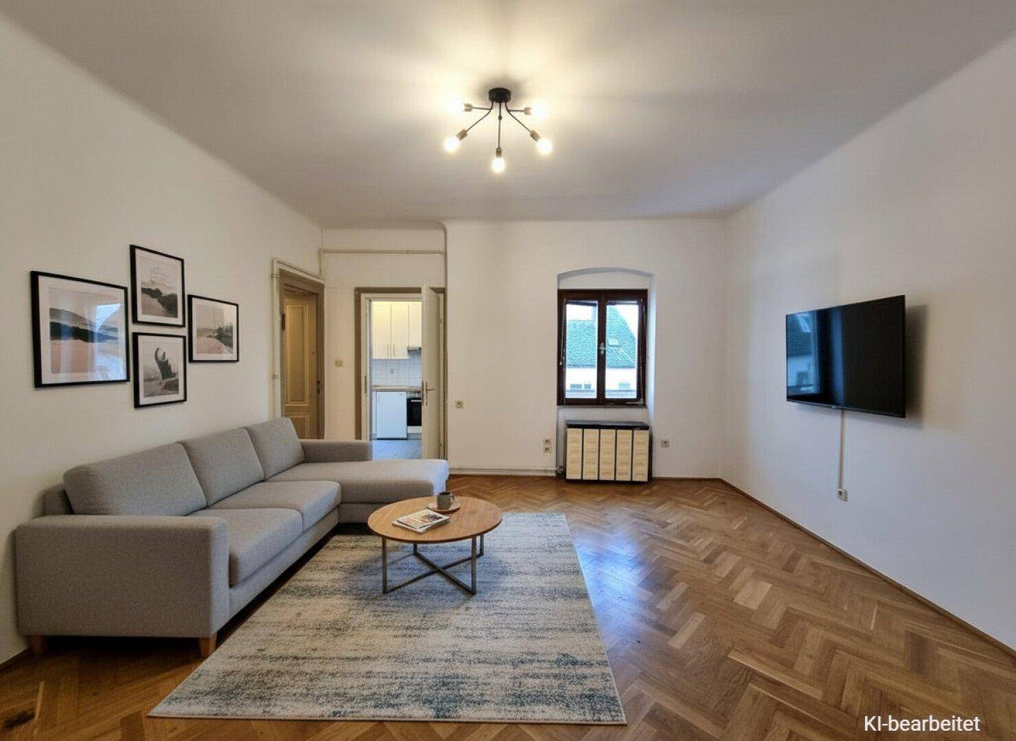 Helles Wohnzimmer mit Fischgrätparkett, modernem Sofa und Wandfernseher.