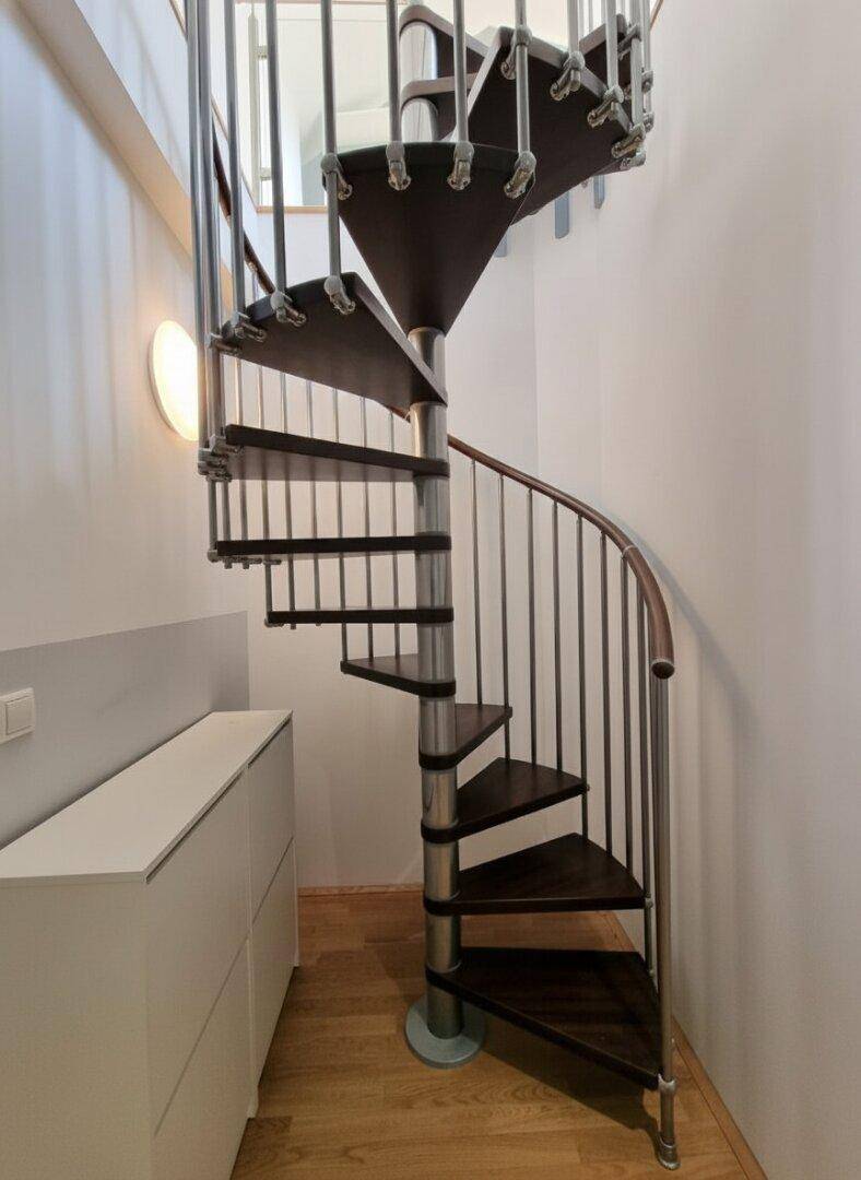 Detailansicht einer modernen Wendeltreppe mit Holzstufen und Metallgeländer.