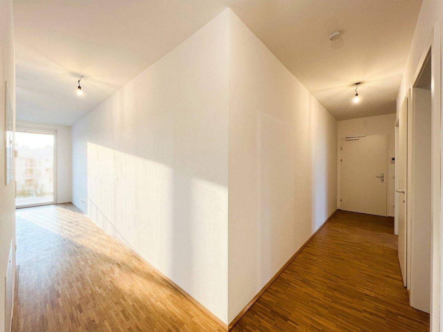 Heller Flur mit Parkettboden und viel Tageslicht, der zu den verschiedenen Räumen führt.