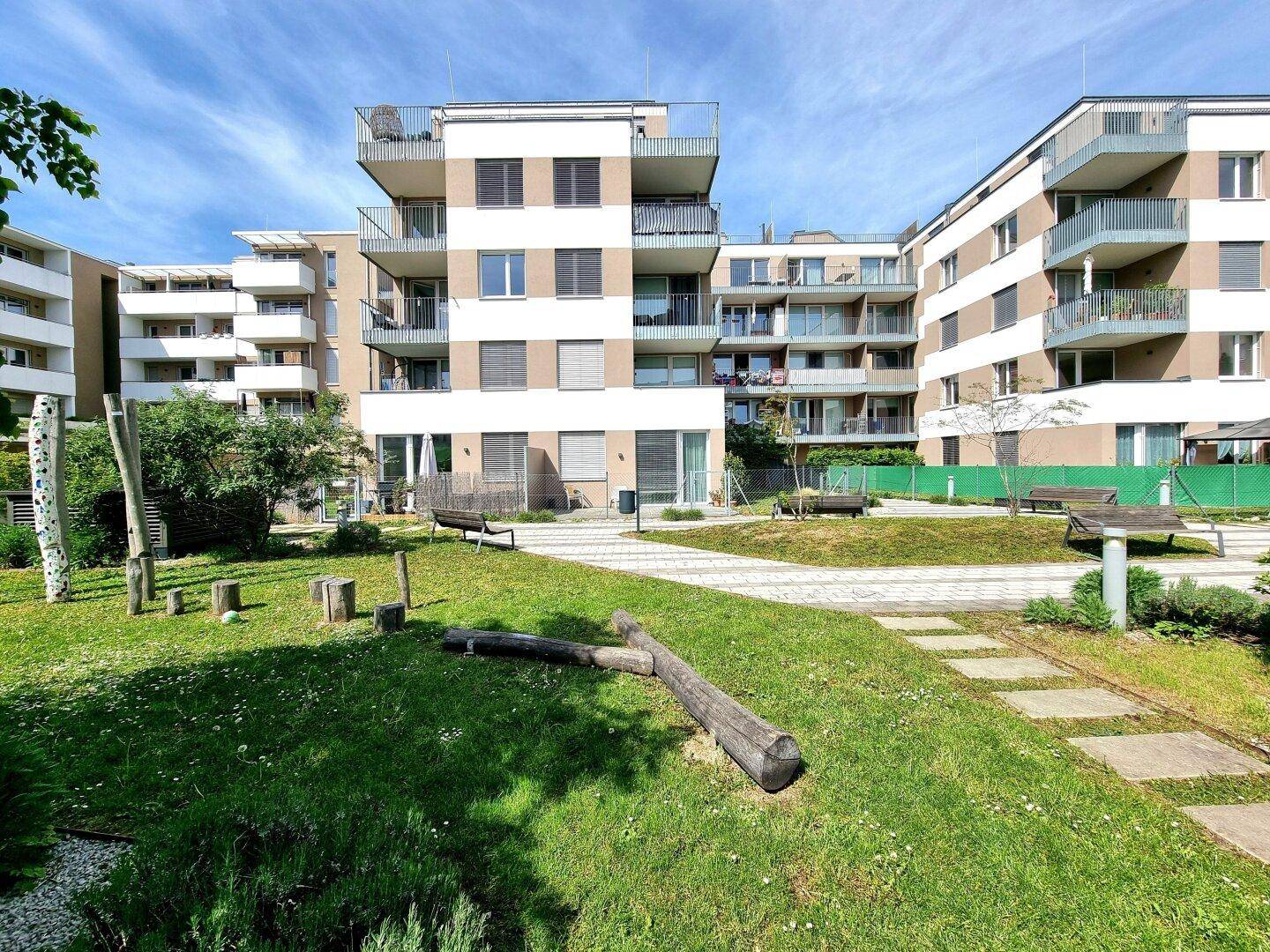 Außenansicht eines modernen Wohnkomplexes mit gepflegter Grünfläche und Spielmöglichkeiten.