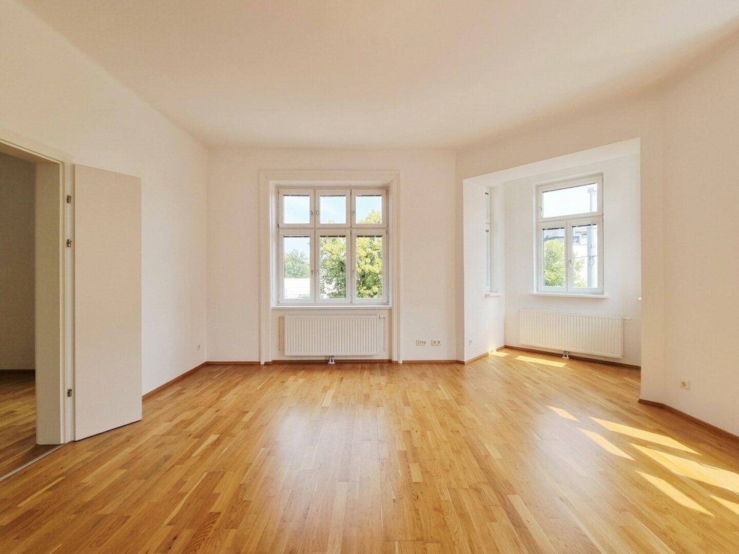 Geräumiges, helles Zimmer mit Eichenparkett und zwei großen Fenstern, bereit zur individuellen Gestaltung.