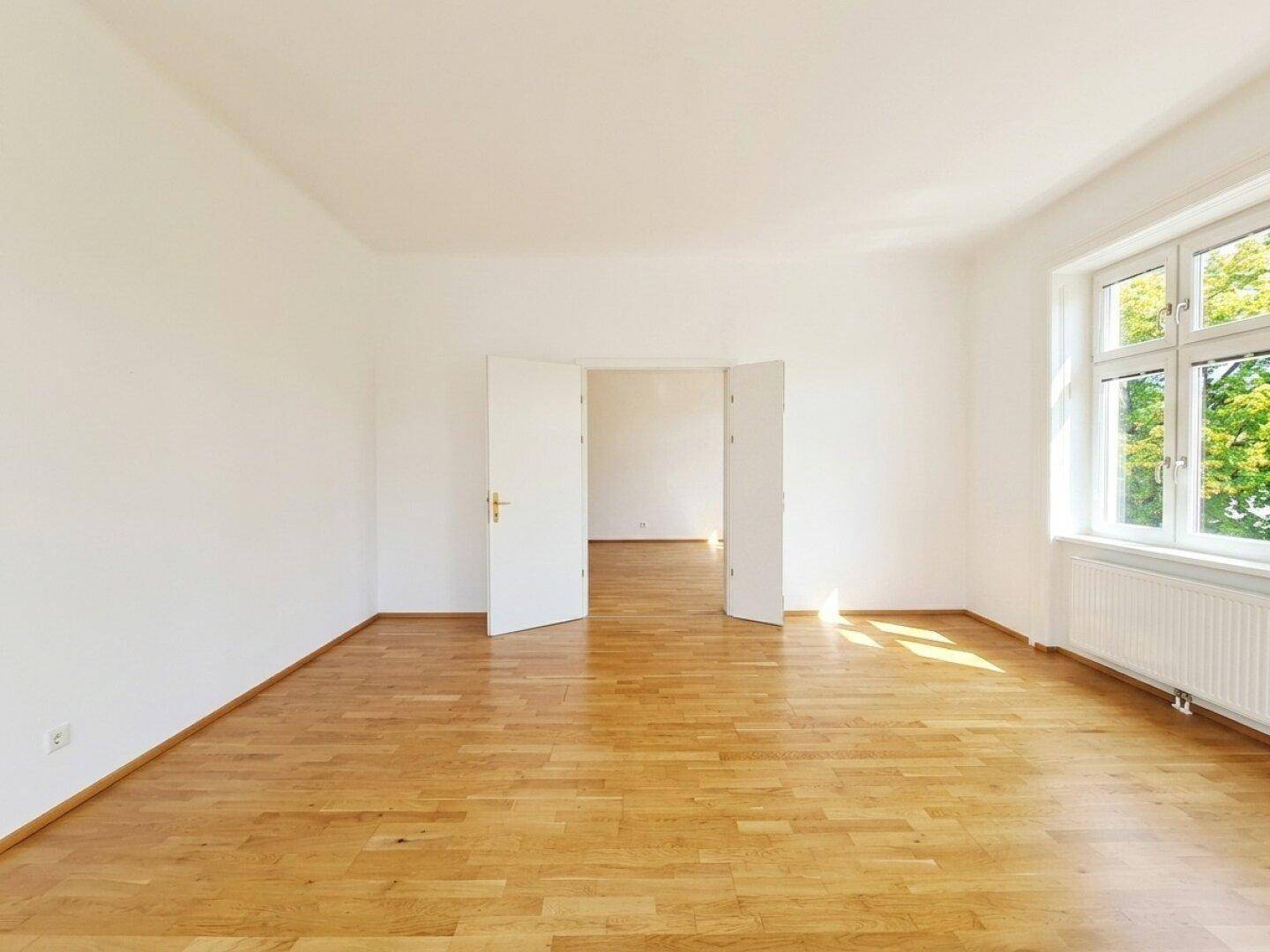 Heller Raum mit Parkettboden und Flügeltüren, der vielseitig genutzt werden kann.