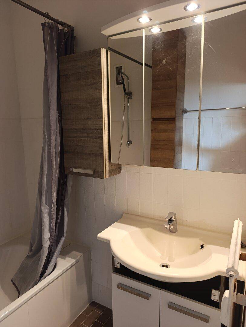 Badezimmer mit Badewanne, Duschvorhang und Spiegelschrank über dem Waschbecken.