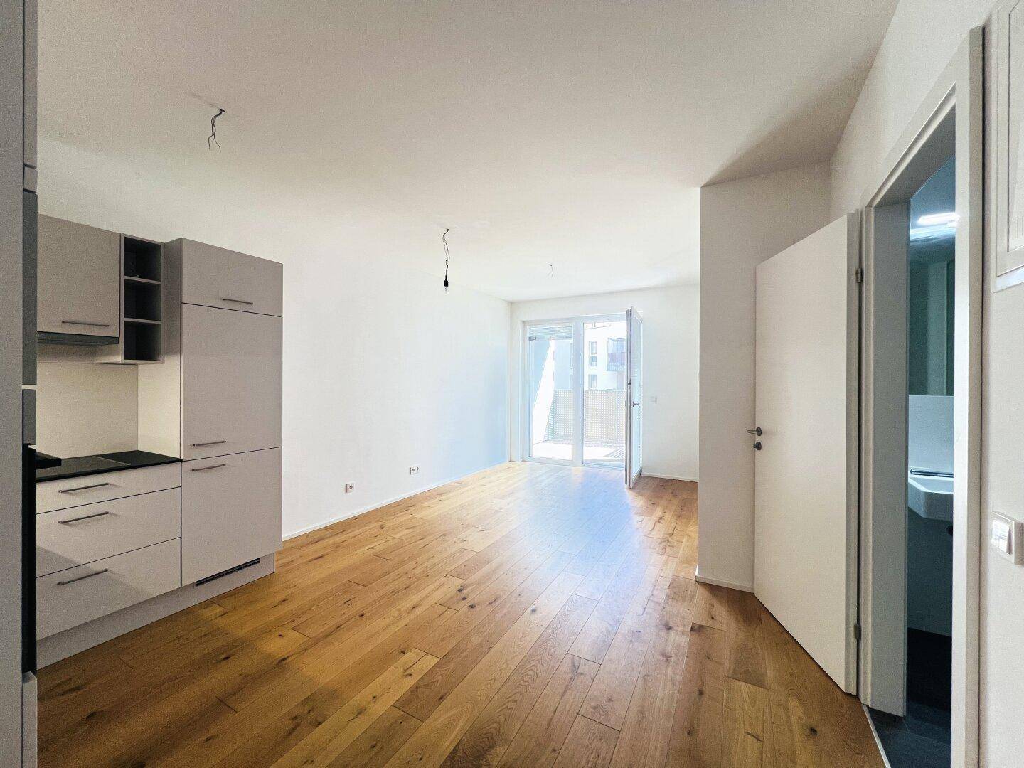 Offener Wohnbereich mit Holzboden und direktem Zugang zu einem Außenbereich.