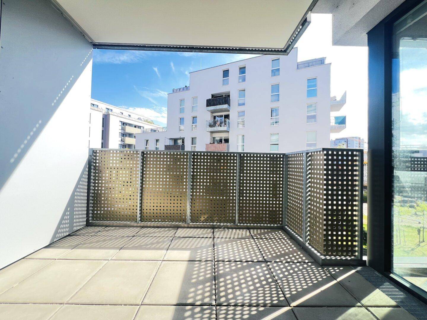 Heller Balkon mit Fliesenboden und Blick auf die umliegenden Gebäude.