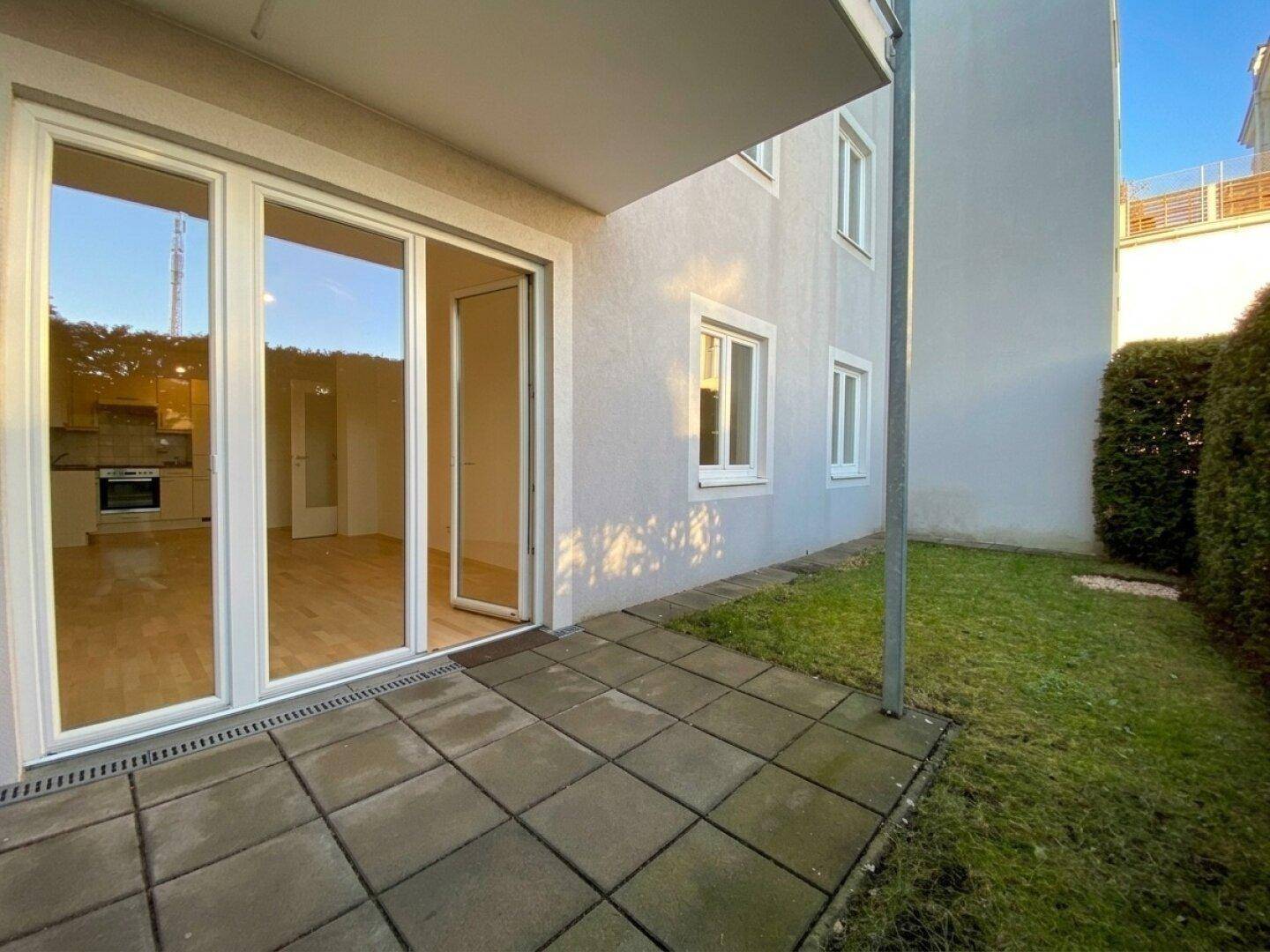 Gepflasterte Terrasse im Erdgeschoss mit direktem Zugang zum Gartenbereich und Blick auf die Umgebung.