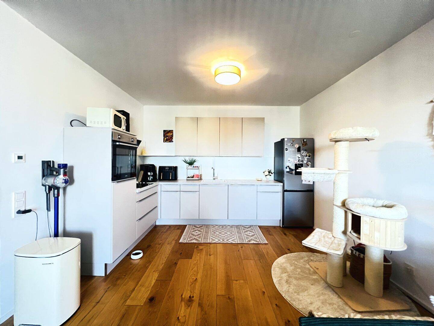 Helle, moderne Küche mit weißen Schränken, integrierten Geräten und Holzboden.