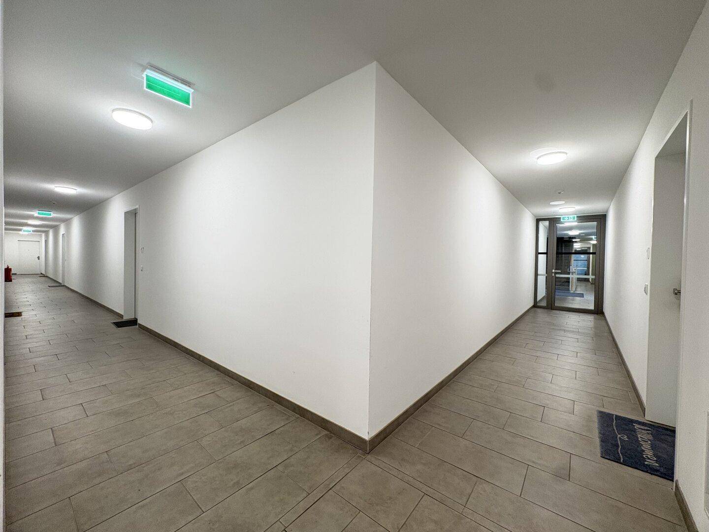 Heller und sauberer Flur im Gebäude mit Fliesenboden und guter Beleuchtung.