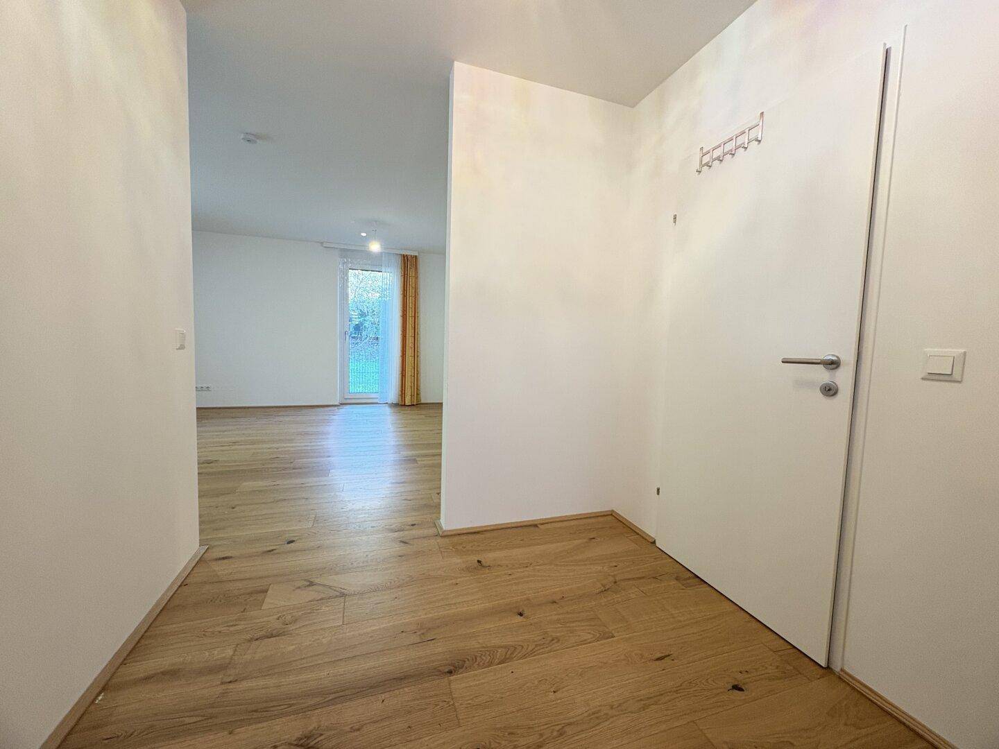 Heller Flur mit Holzboden und Garderobenbereich, der zu den Wohnräumen führt.