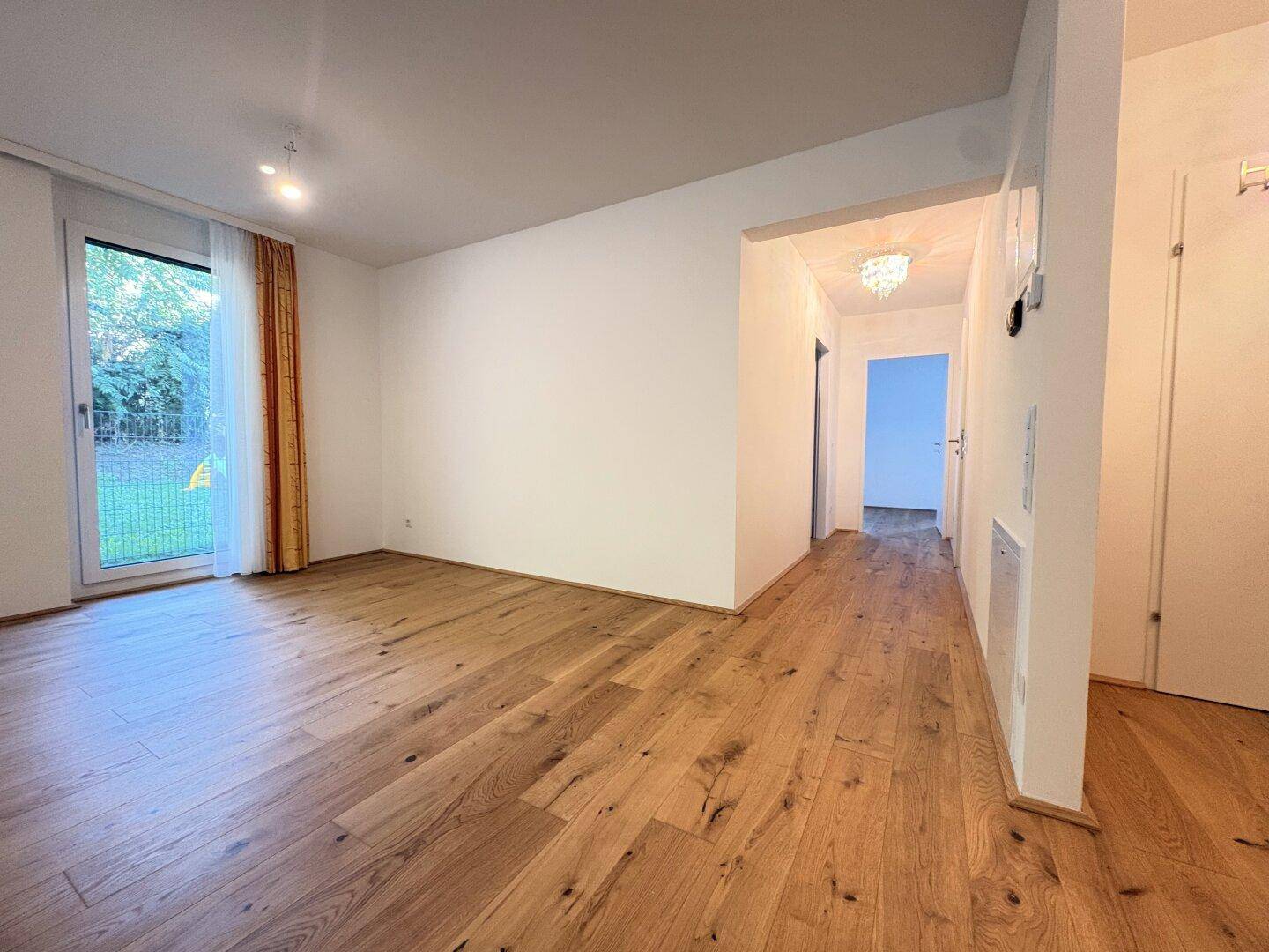 Heller Eingangsbereich mit Holzboden, der in den offenen Wohnbereich führt.