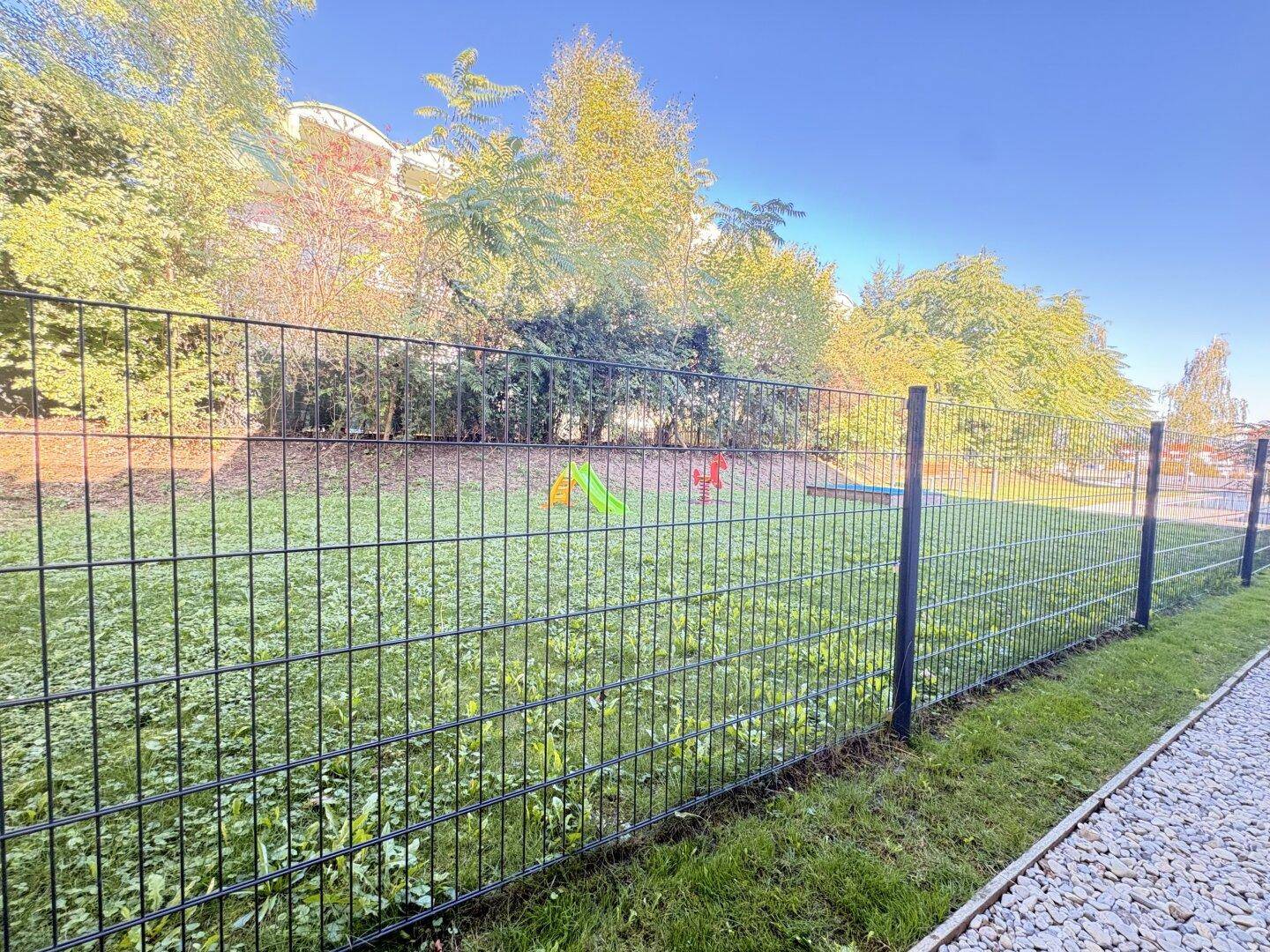 Gemeinschaftlicher Gartenbereich mit Rasenfläche und Spielgeräten für Kinder.